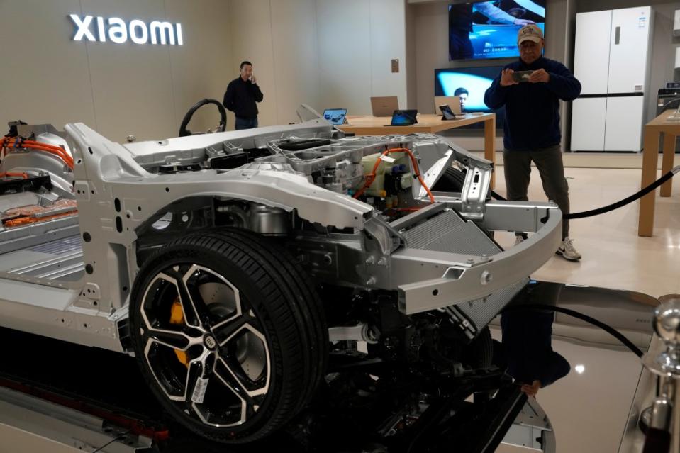 Visitors look at the insides of the SU7 electric car. AP