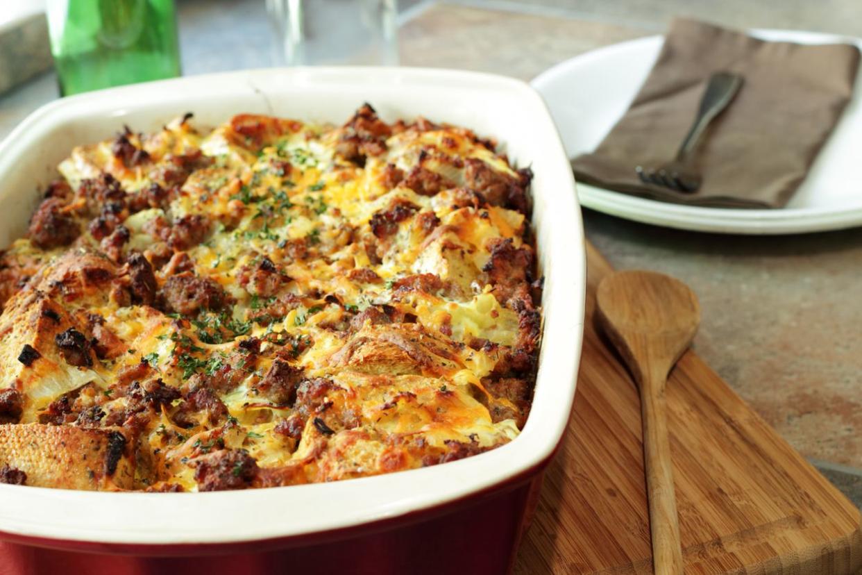 Savory bread pudding in white rectangular baking dish on a wood cutting board and wood spoon