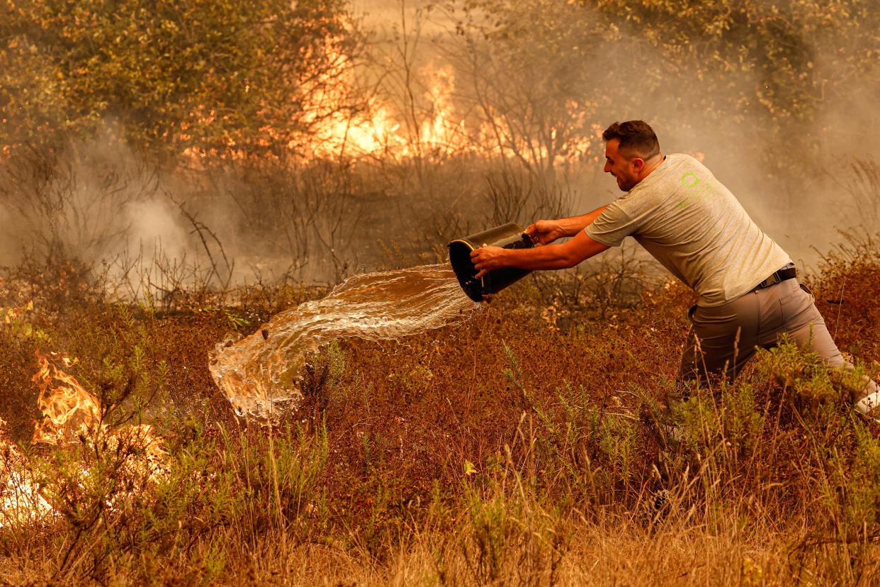 A man throws water on a fire in the municipality of Odemira (EPA)
