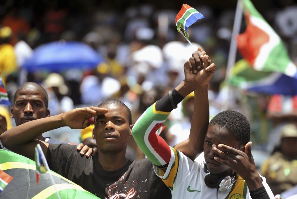A mourner puts his hand to his face as he watches a broadcast of the state funeral of former South African President Nelson Mandela, at Orlando Stadium in Johannesburg
