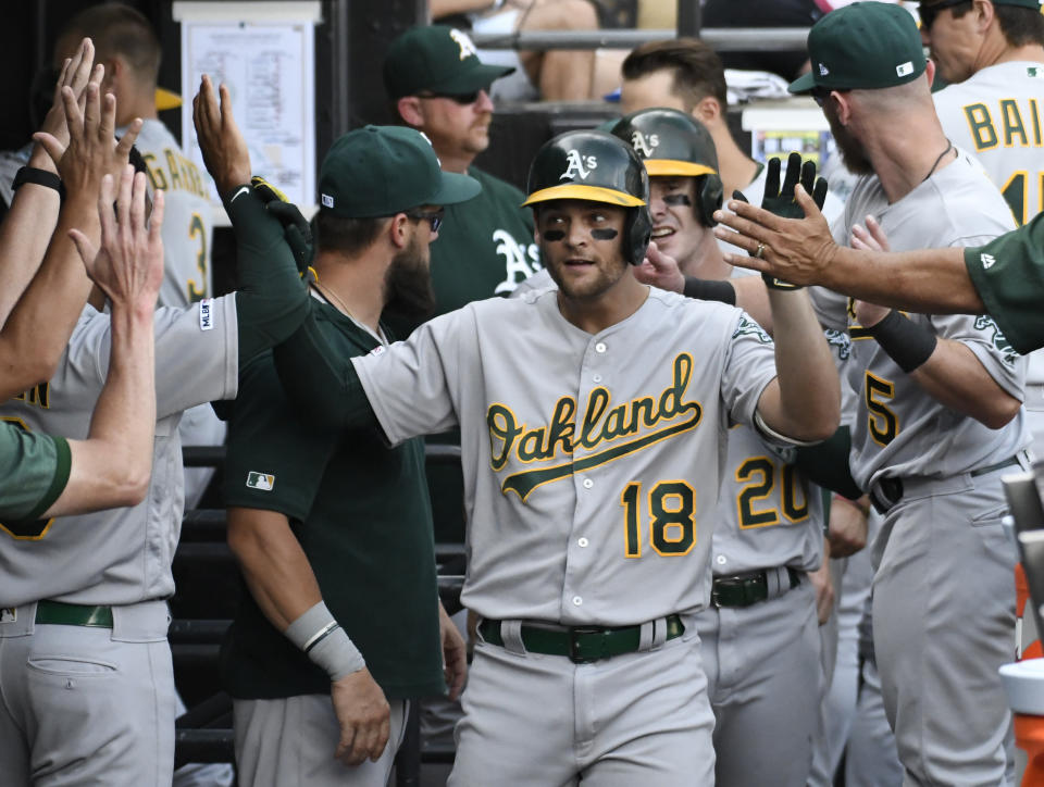 Oakland Athletics' Chad Pinder (18) is greeted in the dugout after hitting a two-run home run against the Chicago White Sox during the eighth inning of a baseball game, Friday, Aug. 9, 2019, in Chicago. (AP Photo/David Banks)