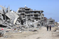 Palestinians walk through the destruction left by the Israeli offensive on Khan Younis, Gaza Strip, Friday, March 8, 2024. (AP Photo/Hatem Ali)