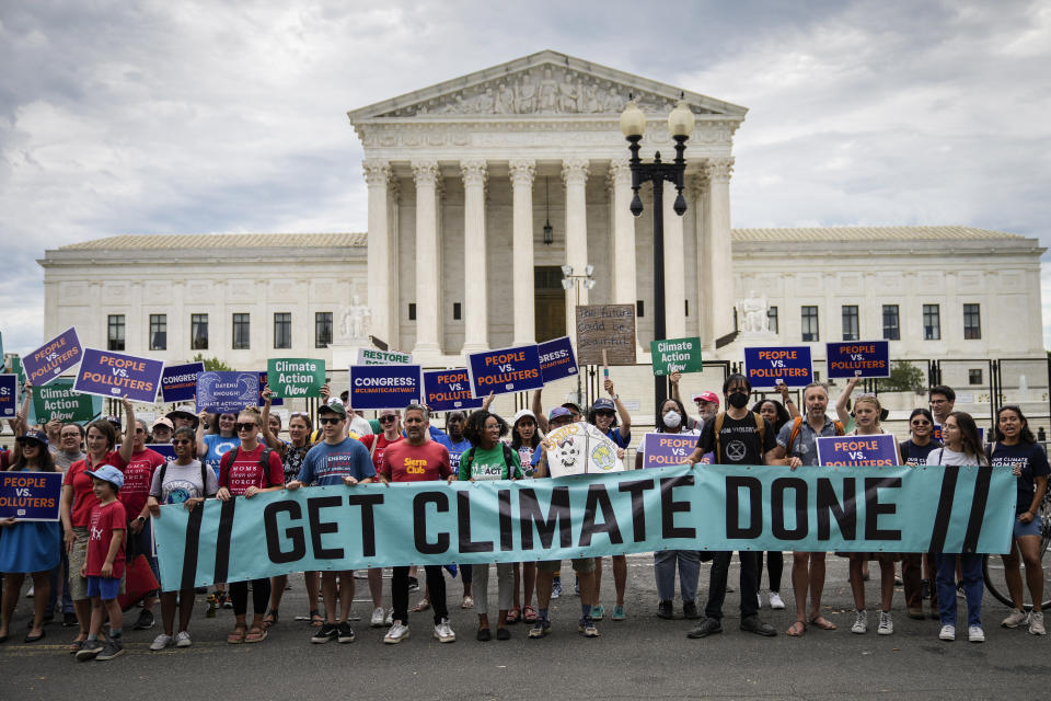 Environmental activists, holding a banner that reads Get Climate Done, rally in front of the Supreme Court.