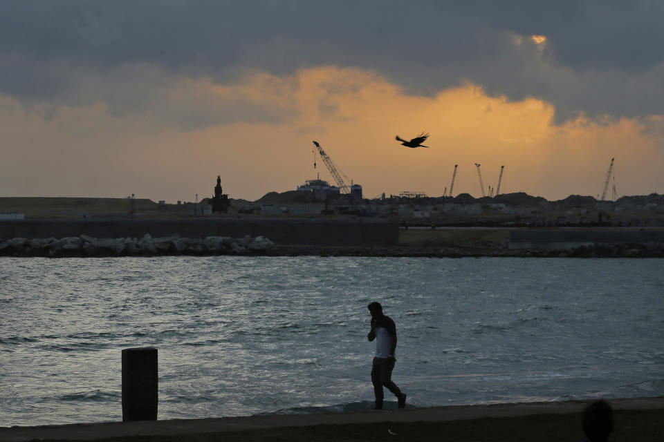 In this July 24, 2019, photo, a Sri Lankan walks by Galle Face, in front of the Chinese-funded sea reclamation project in Colombo, Sri Lanka. Shocks from deadly suicide bombings on Easter Day in Sri Lanka are reverberating throughout its economy in the worst crisis since the South Asian island nation’s civil war ended in 2009. The blasts have devastated Sri Lanka’s vital tourism industry, source of jobs for many, and hindering foreign investment. (AP Photo/Eranga Jayawardena)