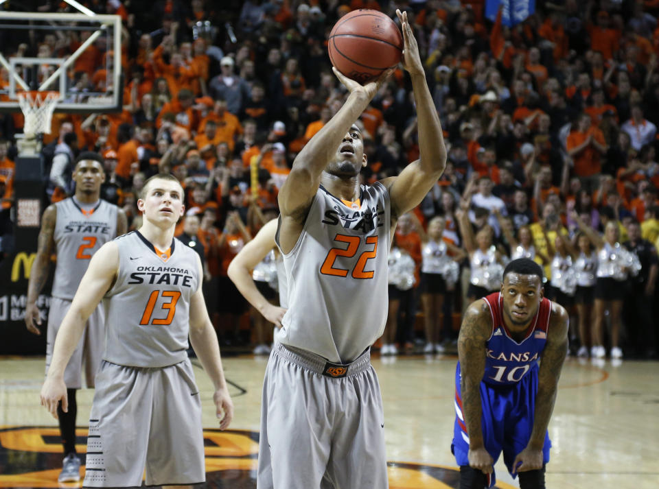 Oklahoma State wing Markel Brown (22) shoots a foul shot in front of teammate Phil Forte (13) and Kansas guard Naadir Tharpe (10) with seconds left in an NCAA college basketball game in Stillwater, Okla., Saturday, March 1, 2014. Oklahoma State won 72-65. (AP Photo/Sue Ogrocki)