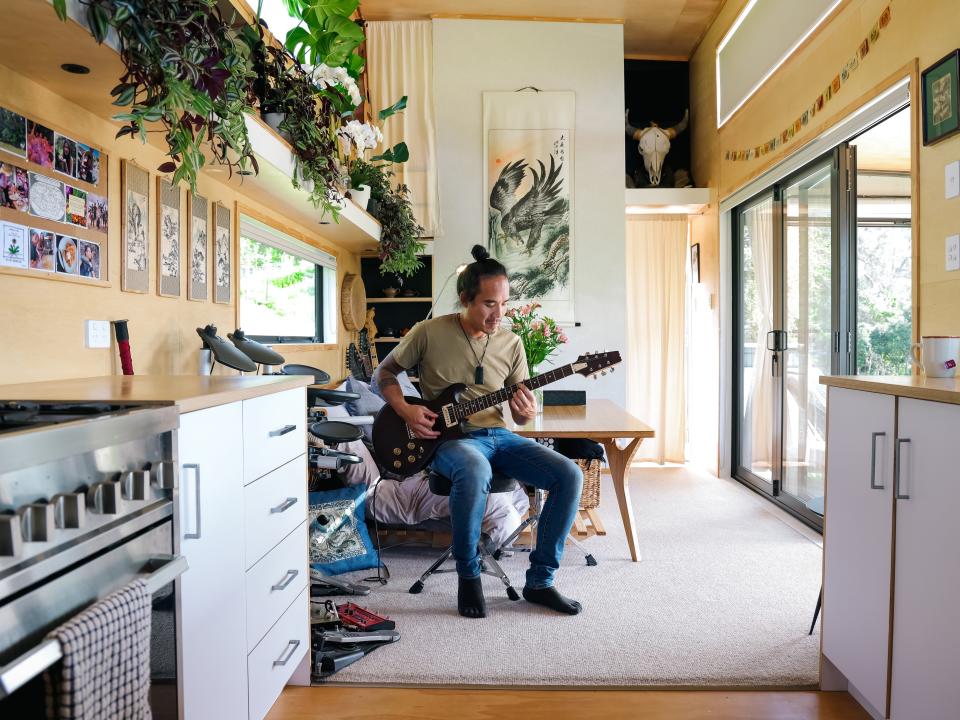 Fabian Low plays the guitar inside his home.