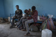 Tigrayan 5-year-old refugee Micheale Gebremariam kisses his 4-month-old sister, Aden, as his 19-year-old uncle, Goytom Tsegay, left, sits with them, inside their family's shelter in Hamdayet, eastern Sudan, near the border with Ethiopia, on March 21, 2021. (AP Photo/Nariman El-Mofty)