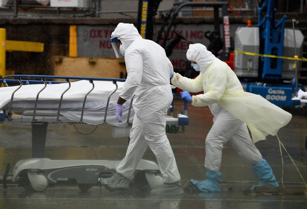 File: Medical personnel move a deceased patient to a refrigerated truck in New York  (AFP via Getty Images)