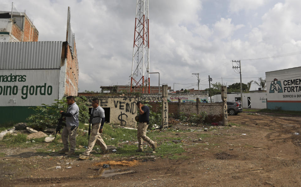 Police pass near the drug rehabilitation center that was attacked the previous day in Irapuato, Mexico, Thursday, July 2, 2020. Gunmen burst into the center and opened fire Wednesday, killing 24 people and wounding seven, authorities said. (AP Photo/Eduardo Verdugo)