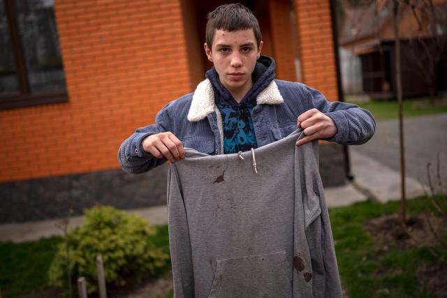 Yura Nechyporenko, 15, holds the hoodie he was wearing the day a Russian soldier tried to kill him in Bucha, on the outskirts of Kyiv, Ukraine, on Tuesday, April 19, 2022. His father was killed, and now his family seeks justice. The hoodie, bloodied at the elbow where a bullet had pierced him, is now the centerpiece of the family&#39;s search for justice. Yura&#39;s mother, Alla, insisted that it not be thrown away.