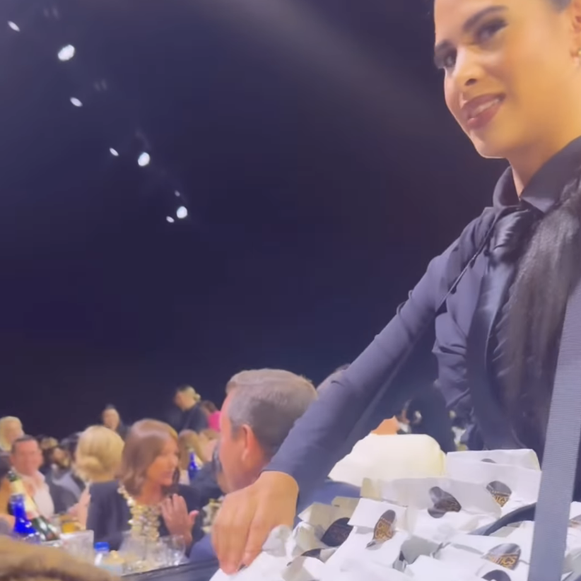 Woman at awards serves pizza in a bag to seated guests