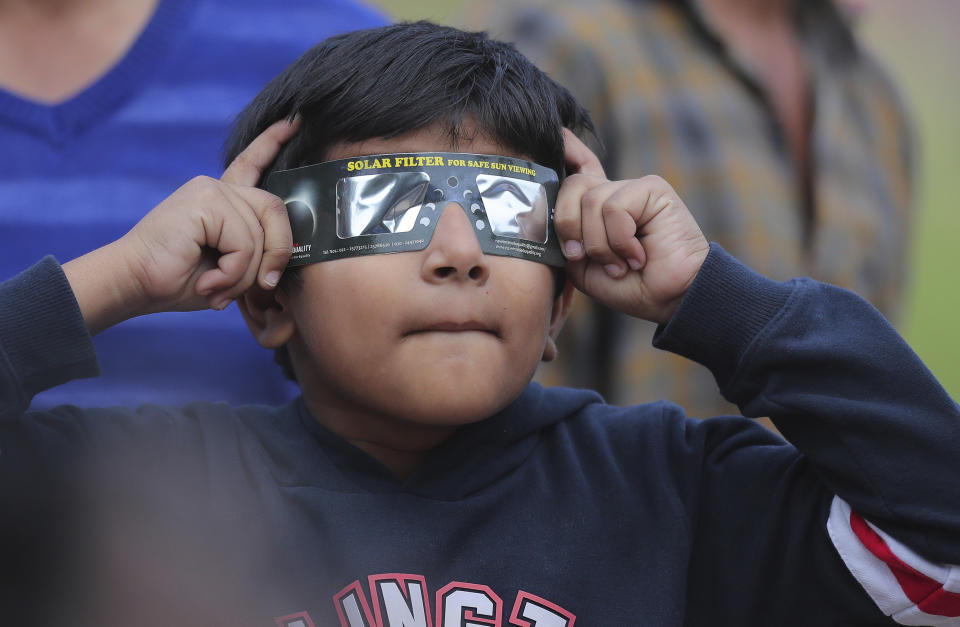 A boy holds a special filter and watches a partial solar eclipse in Hyderabad, India, Thursday, Dec. 26, 2019. (AP Photo/Mahesh Kumar A.)