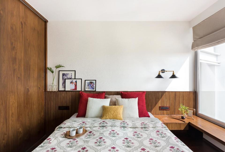 A singular material palette in the second bedroom makes the space look larger. Textures and tones help distinguish the space: deep, chestnut runs underfoot; single veneer sheets climb 10 feet to form the wardrobe shutters; and the headboard is an intricate assembly of pinstriped, teak battens. Bedside lamps by <a href="https://fave.co/2OkFXvo" rel="noopener" target="_blank" data-ylk="slk:The Kaleido Store;elm:context_link;itc:0;sec:content-canvas" class="link ">The Kaleido Store</a>.