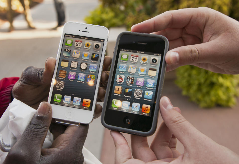 FILE- In this Friday, Sept. 21, 2012, file photo, Noah Meloccaro, right, compares his older iPhone 4s to the new iPhone 5 held by Both Gatwech, outside the Apple Store in Omaha, Neb. Apple Inc. said Monday, Sept. 24, 2012, that it sold more than 5 million units of the iPhone 5 in the three days since its launch, less than analysts had expected. (AP Photo/Nati Harnik, File)