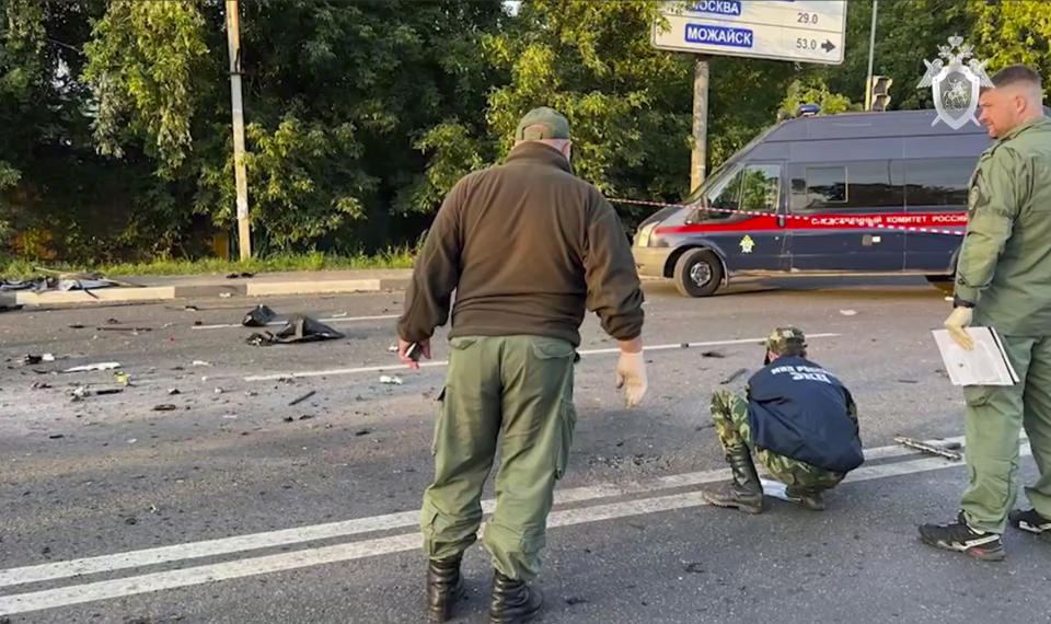 In this handout photo taken from video released by the Investigative Committee of Russia on Aug. 21, investigators work on the site of the explosion of a car purportedly driven by Daria Dugina outside Moscow. 