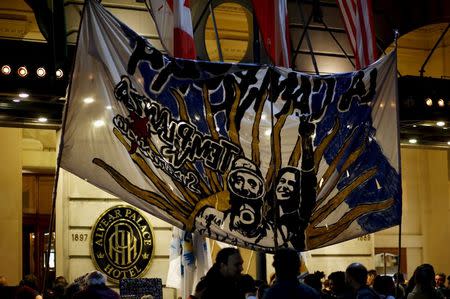 Supporters of presidential candidate Daniel Scioli stand next to a banner with images of late President Nestor Kirchner and Argentina's President Cristina Fernandez de Kirchner outside the Alvear Palace Hotel, where a rally in support of Scioli was being held, in Buenos Aires' Recoleta neighborhood in this picture taken October 20, 2015. REUTERS/Marcos Brindicci