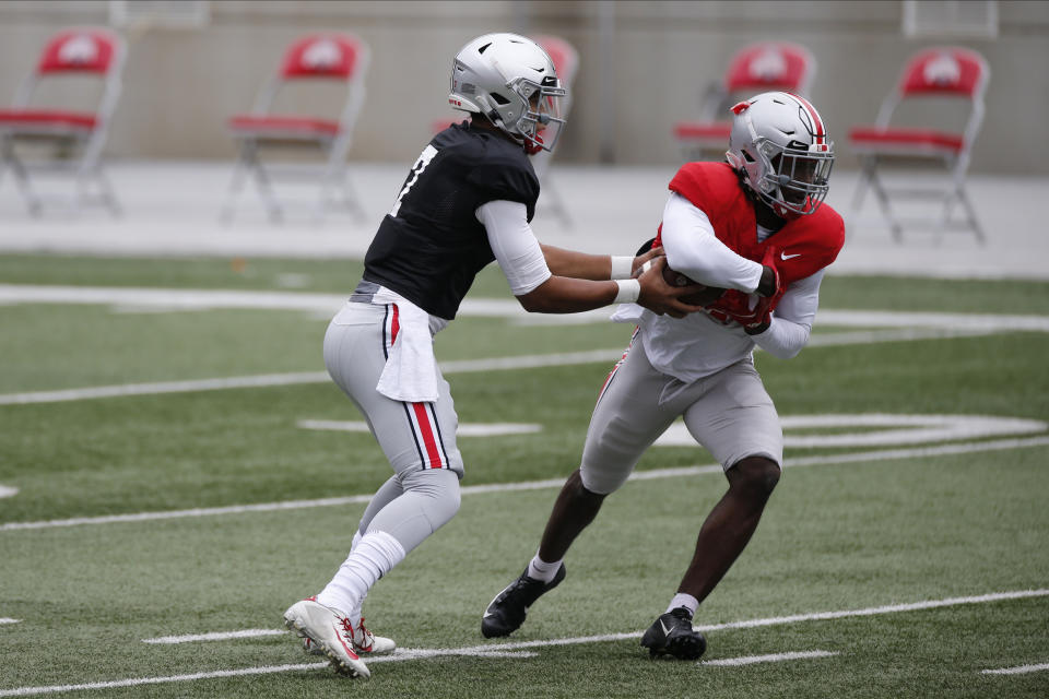 File-This Oct. 3, 2020, file photo shows Ohio State quarterback C.J. Stroud, left, handing the ball to running back Trey Sermon during their NCAA college football practice in Columbus, Ohio. The overarching question this spring is who will be starting at quarterback when the Buckeyes open the season on Sept. 2 at Minnesota. The early departure of Justin Fields for the NFL left two untested backups — pro-style quarterbacks Stroud and Jack Miller III, two of the top prep signal-callers in the country that Ohio State snagged in the 2020 recruiting class. (AP Photo/Jay LaPrete, File)