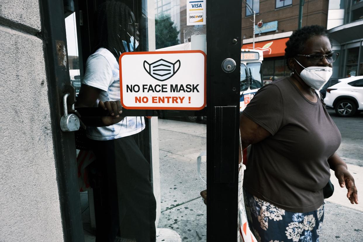 People walk out of a store requesting that people wear masks in Brooklyn, New York.