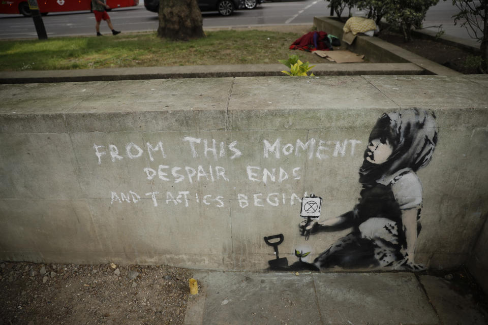 A new piece of street art that people noticed for the first time last night and is believed to be by Banksy stands on a wall where Extinction Rebellion climate protesters had set up a camp in Marble Arch, London, Friday, April 26, 2019. Extinction Rebellion ended its remaining blockades in London on Thursday evening with a closing ceremony, after disrupting the British capital for 10 days. The non-violent protest group is seeking negotiations with the government on its demand to make slowing climate change a top priority. (AP Photo/Matt Dunham)