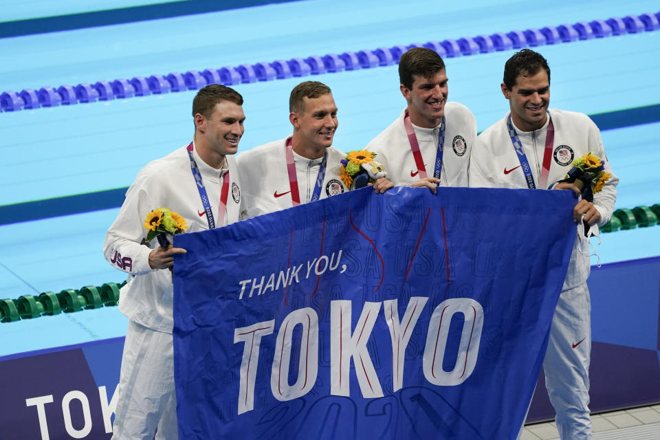 Members of the U.S. men's 4x100-meter medley relay team, Caeleb Dressel, Zach Apple, Ryan Murphy and Michael Andrew, carry a sign that reads, "Thank you, Tokyo," after winning the gold medal at the 2020 Summer Olympics, Sunday, Aug. 1, 2021, in Tokyo, Japan. (AP Photo/Jae C. Hong)