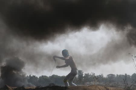 A Palestinian protester uses a sling to hurl stones at Israeli troops during clashes near border between Israel and Central Gaza Strip October 23, 2015. REUTERS/Ibraheem Abu Mustafa