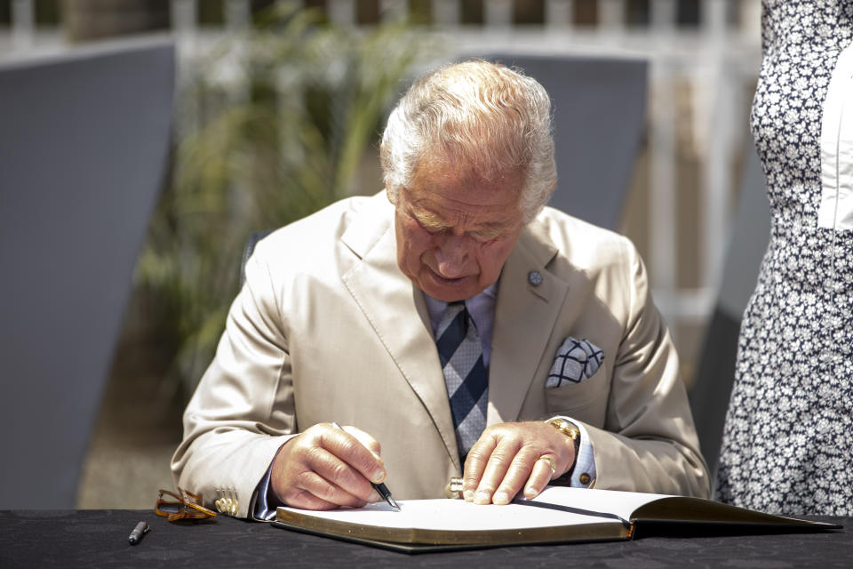 Britain's Prince Charles signs the visitors book at the Kigali Genocide Memorial in the capital Kigali, Rwanda Wednesday, June 22, 2022. Prince Charles has become the first British royal to visit Rwanda, representing Queen Elizabeth II as the ceremonial head of the Commonwealth at a summit where both the 54-nation bloc and the monarchy face uncertainty. (AP Photo)