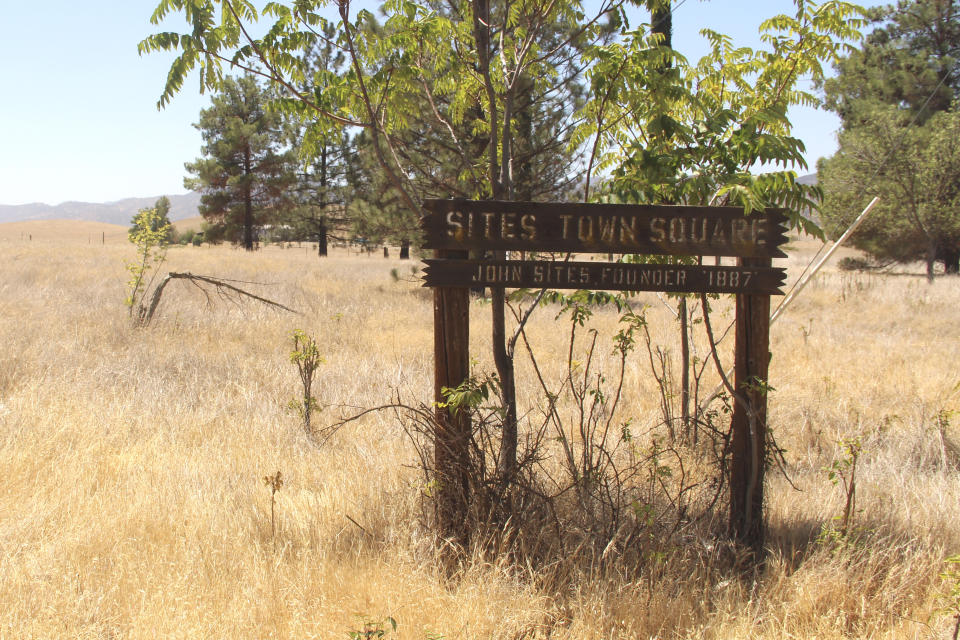 Dry grass surrounds a sign denoting the Sites Town Square on Friday, July 23, 2021 in Sites, Calif. The sign is one of the few remnants of the once bustling town anchored by a sandstone quarry. The town would be underwater as part of the planned Sites Reservoir. The reservoir would be used to store water during wet years for use during droughts and would be large enough to supply 1.5 million households each for one year. (AP Photo/Adam Beam)