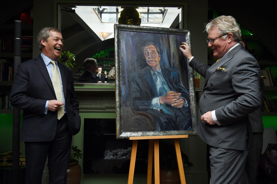 Nigel Farage stands beside a portrait of himself titled Mr Brexit by artist Dan Llywelyn Hall, with Comedian Jim Davidson (right), at L'Escargot Restaurant in London.