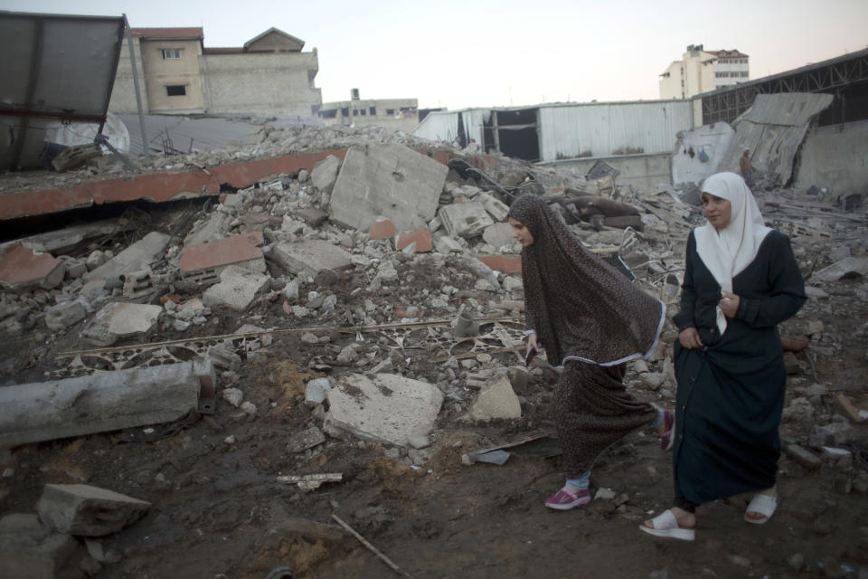 Two Palestinians women walk past the rubble of buildings destroyed by Israeli airstrikes early morning in Gaza City, Saturday, Oct. 27, 2018. Israeli aircraft have struck dozens of militant sites across the Gaza Strip as militants fired some 30 rockets into Israel. (AP Photo/Khalil Hamra)