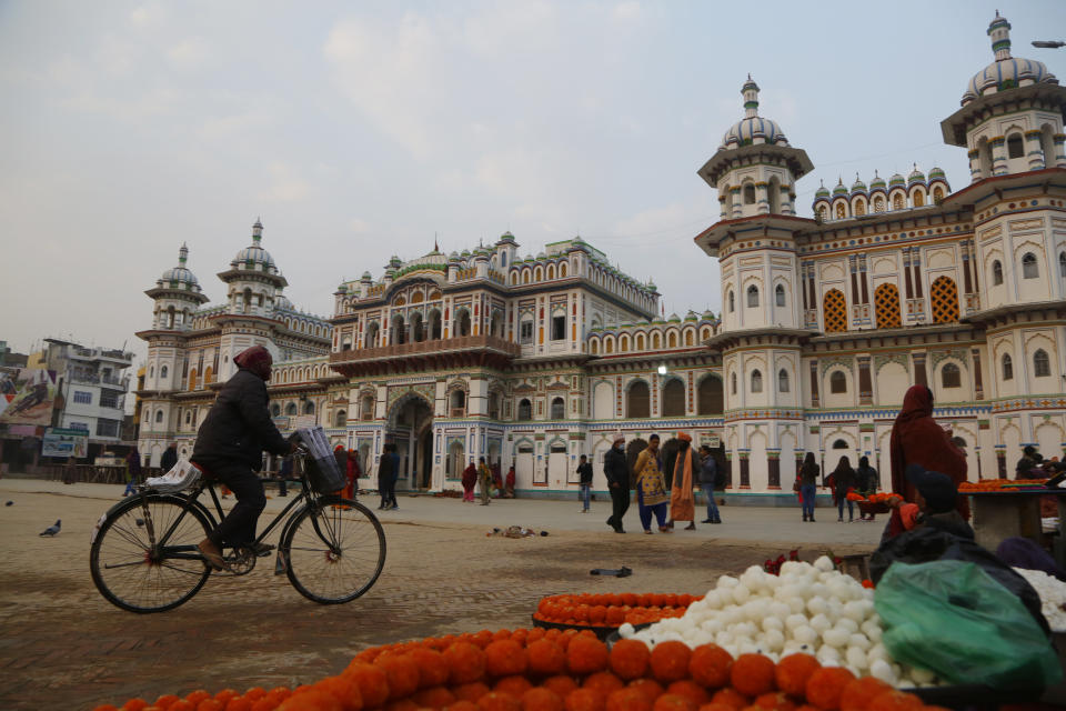 In this Nov. 30, 2018 photo, a Nepalese man rides his bicycle in front of the Ram Janaki temple in Janakpur, Nepal. Millions of Hindu devotees travel every year to the temple where the Hindu goddess Sita is believed to have been born and later married the Hindu god Ram. A new rail line connecting the 34 kilometers (21 miles) between Janakpur in southeastern Nepal and Jay Nagar in the Indian state of Bihar are raising hopes for new business and pilgrimages. (AP Photo/Niranjan Shrestha)