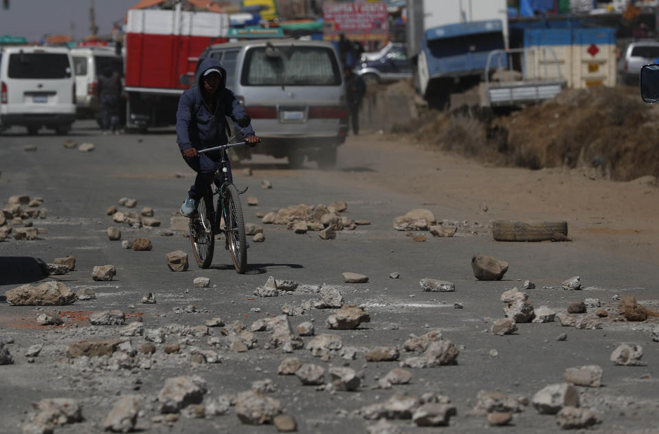 Un ciclista atraviesa piedras colocadas por manifestantes que protestan contra el aplazamiento de las elecciones presidenciales en El Alto, Bolivia, el lunes 3 de agosto de 2020. La máxima autoridad electoral de Bolivia retrasó las elecciones presidenciales del 6 de septiembre al 18 de octubre. (AP Foto/Juan Karita)