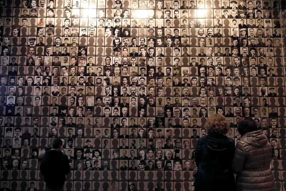 In this photo taken Saturday, March 21, 2015, visitors look at portraits of victims at the Holocaust Museum in the town of Kalavryta, western Greece. The Nazis deported Greece's Jews to death camps in Poland.