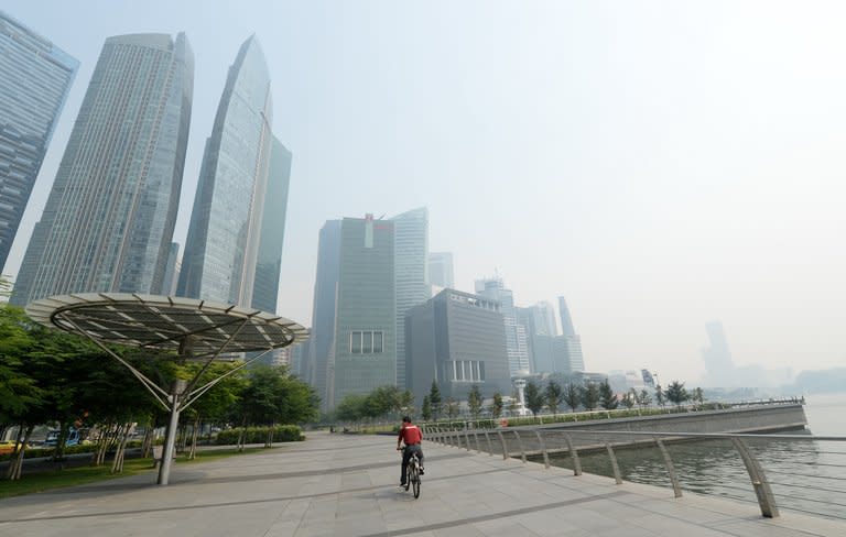 A cyclist rides along the pier in front of buildings blanketed by haze in Singapore on June 19, 2013. Singapore's smog problem from forest fires in Indonesia worsened Wednesday as air pollutant levels reached a 16-year high