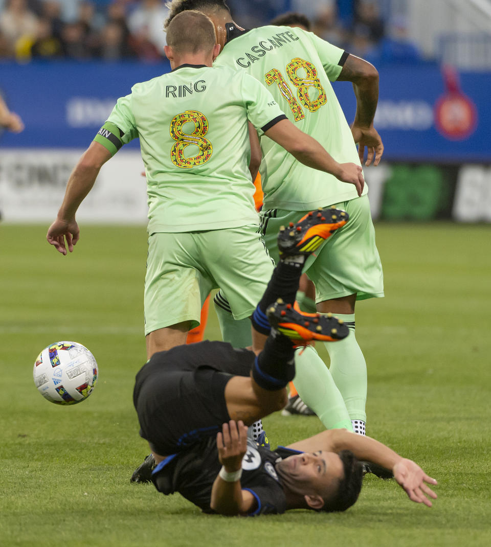 CF Montréal midfielder Joaquín Torres (10) falls to the turf after losing possession of the ball to Austin FC midfielder Alexander Ring (8) and defender Julio Cascante (18) during the first half of an MLS soccer match in Montreal on Saturday, June 18, 2022. (Peter McCabe/The Canadian Press via AP)
