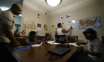 Arlena Brown, center, holds her youngest child, Lucy, 9 months, as she and husband, Robert, left, lead their other children, from left, Jacoby, 11; Felicity, 9, and Riley, 10, through math practice at their home in Austin, Texas, Tuesday, July 13, 2021. “I didn’t want my kids to become a statistic and not meet their full potential,” said Robert, a former teacher who now does consulting. “And we wanted them to have very solid understanding of their faith.” (AP Photo/Eric Gay)