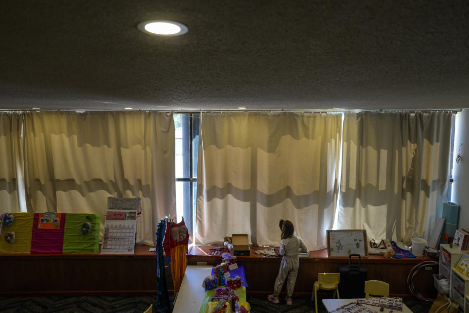 A girl, evacuated from Kiryat Shmona, reads inside a hall turned in to a kindergarten at the hotel in Tiberias, northern Israel, Tuesday, March 5, 2024. Around 60,000 Israelis who evacuated from cities and towns along the border with Lebanon are grappling with the question of when they will be able to return home. Hezbollah began launching rockets towards Israel one day after Hamas-led militants stormed into southern Israel on Oct. 7. (AP Photo/Ariel Schalit)