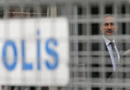 A member of the security personnel guarding Saudi Arabia's consulate is seen behind barriers blocking the road leading to the diplomatic mission, in Istanbul, Tuesday, Oct. 23, 2018. S The Turkish president is expected to announce details Tuesday of his country's investigation into the killing of Saudi writer Jamal Khashoggi, as skepticism intensified about Saudi Arabia's account that he died accidentally in its consulate in Istanbul. (AP Photo/Lefteris Pitarakis)