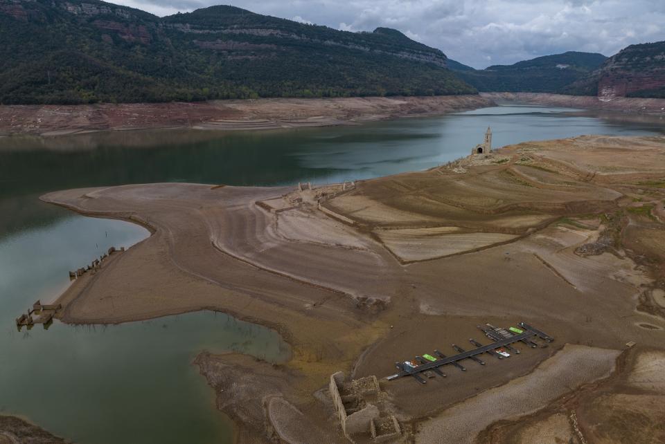 Dry, cracked land is visible around at the Sau reservoir, about 100 km (62 miles) north of Barcelona, Spain, Tuesday, April 18, 2023. (AP Photo/Emilio Morenatti)