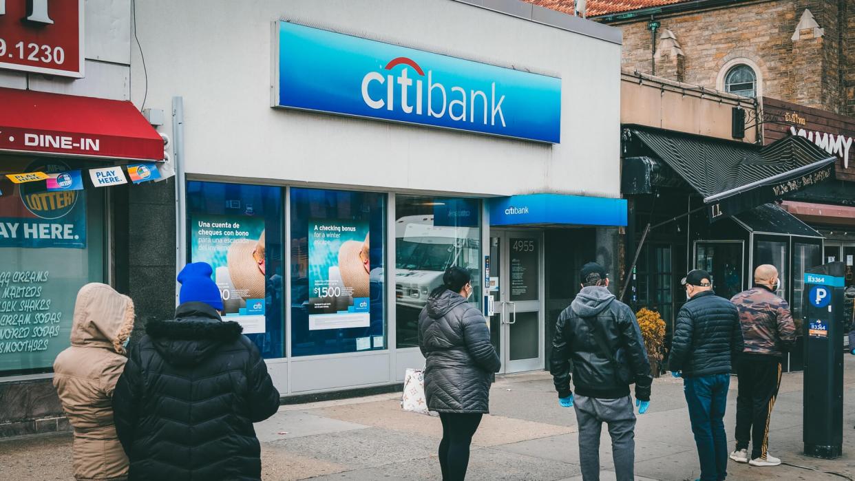 New York, NY - April 16, 2020: People waiting in line keeping social distances to get into bank for financial transactions amid COVID-19 pandemic in Inwood neighborhood of Manhattan.