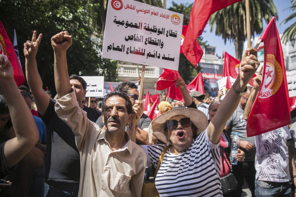 Supporters of the Tunisian General Labor Union (UGTT) gather during a rally outside its headquarters in Tunis, Tunisia, Thursday, June 16, 2022. A nationwide public sector strike in Tunisia is poised to paralyze land and air transportation and other vital activities with the North African nation already in the midst of a deteriorating economic crisis. Writing on placard reads “Public and private sectors are important support for the public” (AP Photo/Hassene Dridi)