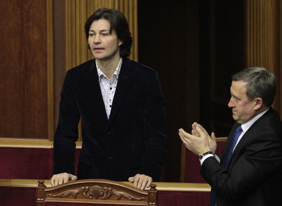 Actor Yevhen Nishchuk, left, who served as Master of Ceremonies on a big stage on Kiev’s Independence Square, stands in parliament after being appointed Culture Minister, Kiev, Ukraine, Thursday, Feb. 27, 2014. Top figures in Ukraine's three-month protest are taking up powerful posts in the new Cabinet, underscoring the powerful and unpredictable force of the revolt. But while few doubt the leaders' resolve, the nominations have raised questions about their skills and expertise — especially given the enormous challenges the new government faces. (AP Photo/Sergei Chuzavkov)