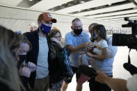 A reunited family are interviewed by the media after some of them arrived on a flight, at Terminal 5 of Heathrow Airport in London, Monday, Aug. 2, 2021. Travelers fully vaccinated against coronavirus from the United States and much of Europe were able to enter Britain without quarantining starting today, a move welcomed by Britain's ailing travel industry. (AP Photo/Matt Dunham)