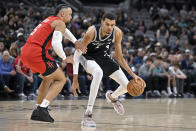 San Antonio Spurs' Victor Wembanyama, right, drives against Houston Rockets' Dillon Brooks during the first half of an NBA basketball game Tuesday, March 12, 2024, in San Antonio. (AP Photo/Darren Abate)