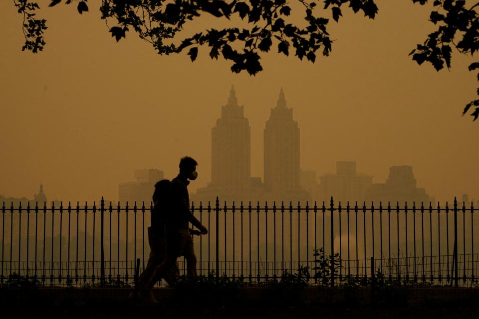 TOPSHOT - People walk in Central Park as smoke from wildfires in Canada cause hazy conditions in New York City on June 7, 2023. Smoke from Canada's wildfires has engulfed the Northeast and Mid-Atlantic regions of the US, raising concerns over the harms of persistent poor air quality. (Photo by TIMOTHY A. CLARY / AFP) (Photo by TIMOTHY A. CLARY/AFP via Getty Images)