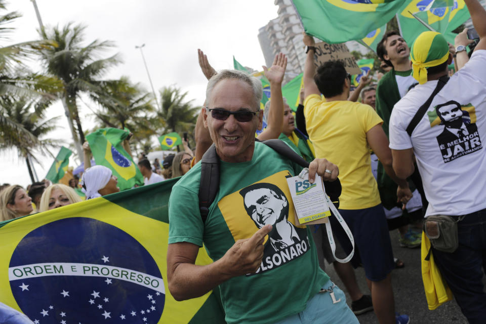 Supporters of Brazilian presidential candidate Jair Bolsonaro cheer as they gather outside his residence in Rio de Janeiro, Brazil, Sunday, Oct. 28, 2018, during the country's presidential runoff election. Brazilians on Sunday were weighing their hunger for radical change against fears that Bolsonaro, the presidential front-runner, could threaten democracy as they cast ballots in the culmination of a bitter campaign that split many families and was frequently marred by violence. (AP Photo/Silvia Izquierdo)