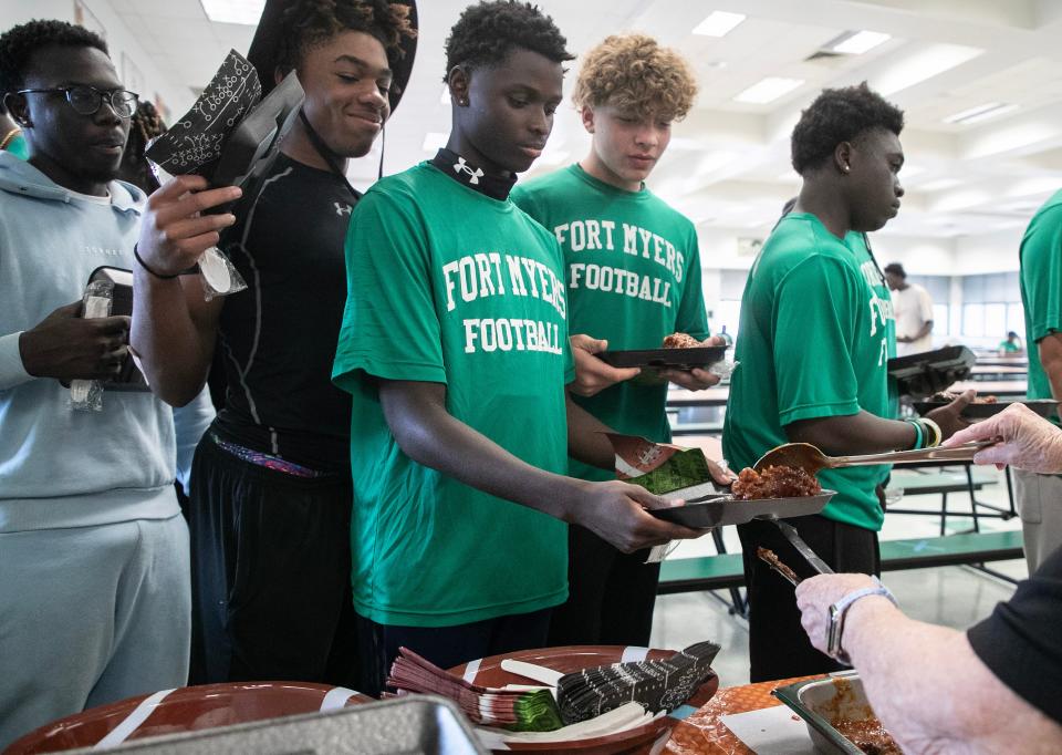 Fort Myers High School football players line up for their pre-game meal on Thursday, Oct. 19, 2023, at Fort Myers High School. Volunteers make a meal for the students to eat before each game.