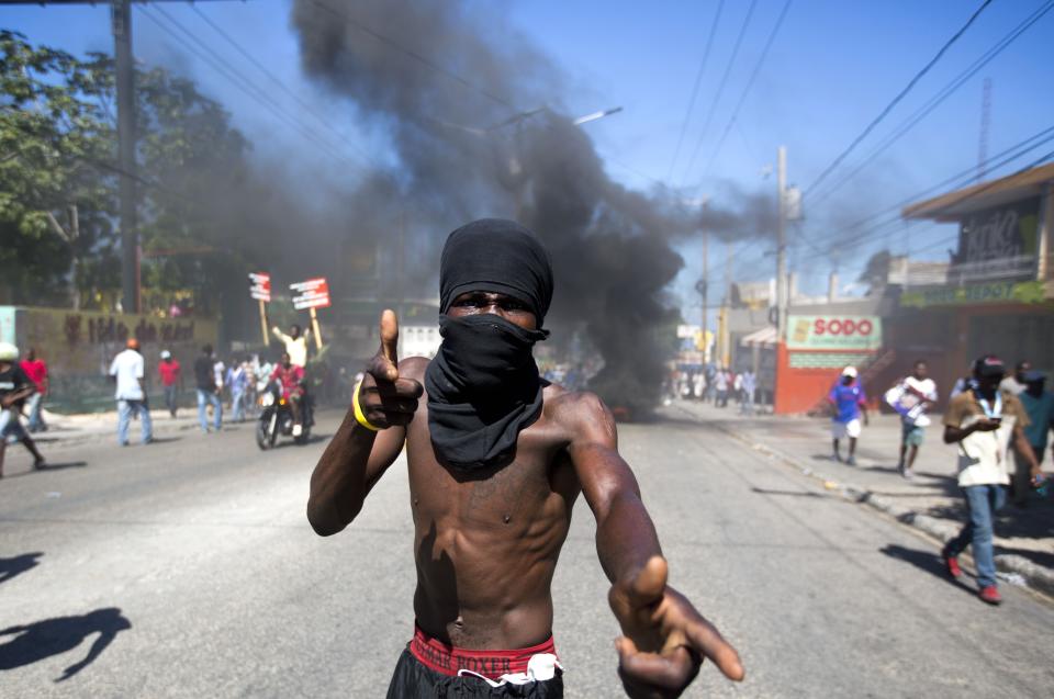 In this Oct. 17, 2018 photo, a masked man joins a protests demanding to know how Petro Caribe funds have been used by the current and past administrations, in Port-au-Prince, Haiti. Much of the financial support to help Haiti rebuild after the 2010 earthquake comes from Venezuela's Petro Caribe fund, a 2005 pact that gives suppliers below-market financing for oil and is under the control of the central government. (AP Photo/Dieu Nalio Chery)