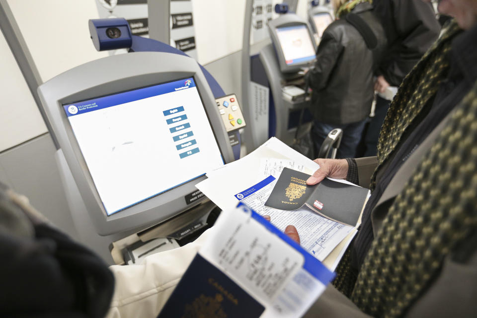 TORONTO, ON - DECEMBER 4: Travellers take a moment to figure out the new machines. With holiday travel set to increase, Pearson Airport and U.S. Border and Customs officials invite media to see 40 automated processing kiosks -- that should speed up wait times. The kiosks that are in use at seven other airports have reduced wait times by more than 35 per cent. December 4, 2013.        (Richard Lautens/Toronto Star via Getty Images)