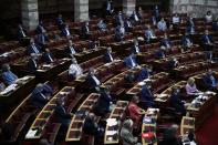 Lawmakers wearing face masks and social distancing to curb the spread of the coronavirus, attend a parliament debate in Athens, Wednesday, Aug. 26, 2020. Greece's Prime Minister Kyriakos Mitsotakis says his country is planning to exercise its legal right to extend territorial waters along its western coastline from six to 12 nautical miles. The plan was announced Wednesday as Greece remains locked in an escalating dispute over maritime boundaries with neighbor Turkey, with a survey mission and military exercises currently being held in east Mediterranean waters claimed by both countries. (AP Photo/Thanassis Stavrakis)