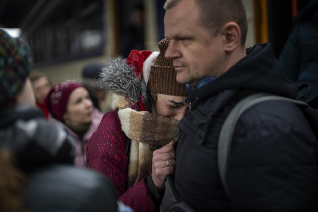 A woman cries as she says goodbye to her husband before boarding a train bound for Lviv at the Kyiv station on Thursday. Ukrainian men have to stay to fight in the war while women and children are leaving the country to seek refuge in neighboring countries.